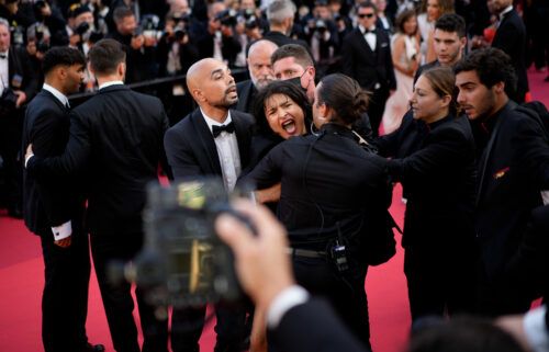 A protester wearing body paint that reads "Stop Raping Us" in the color of the Ukrainian flag is removed from the Cannes red carpet.