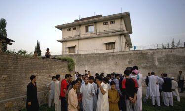 Residents gather outside a house