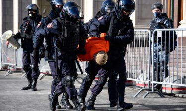 Police officers detain a man during a protest against Russian military action in Ukraine