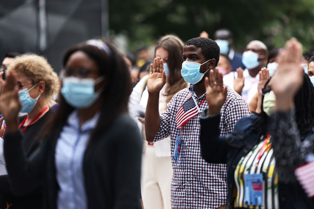 <i>Michael M. Santiago/Getty Images</i><br/>People raise their hands as they take the Oath of Allegiance during a naturalization ceremony on September 17