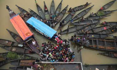 People gather to collect food aid in a flooded area in Companiganj