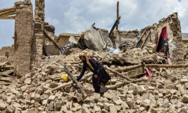 An Afghan man looks for his belongings amid the ruins of a house damaged by an earthquake.