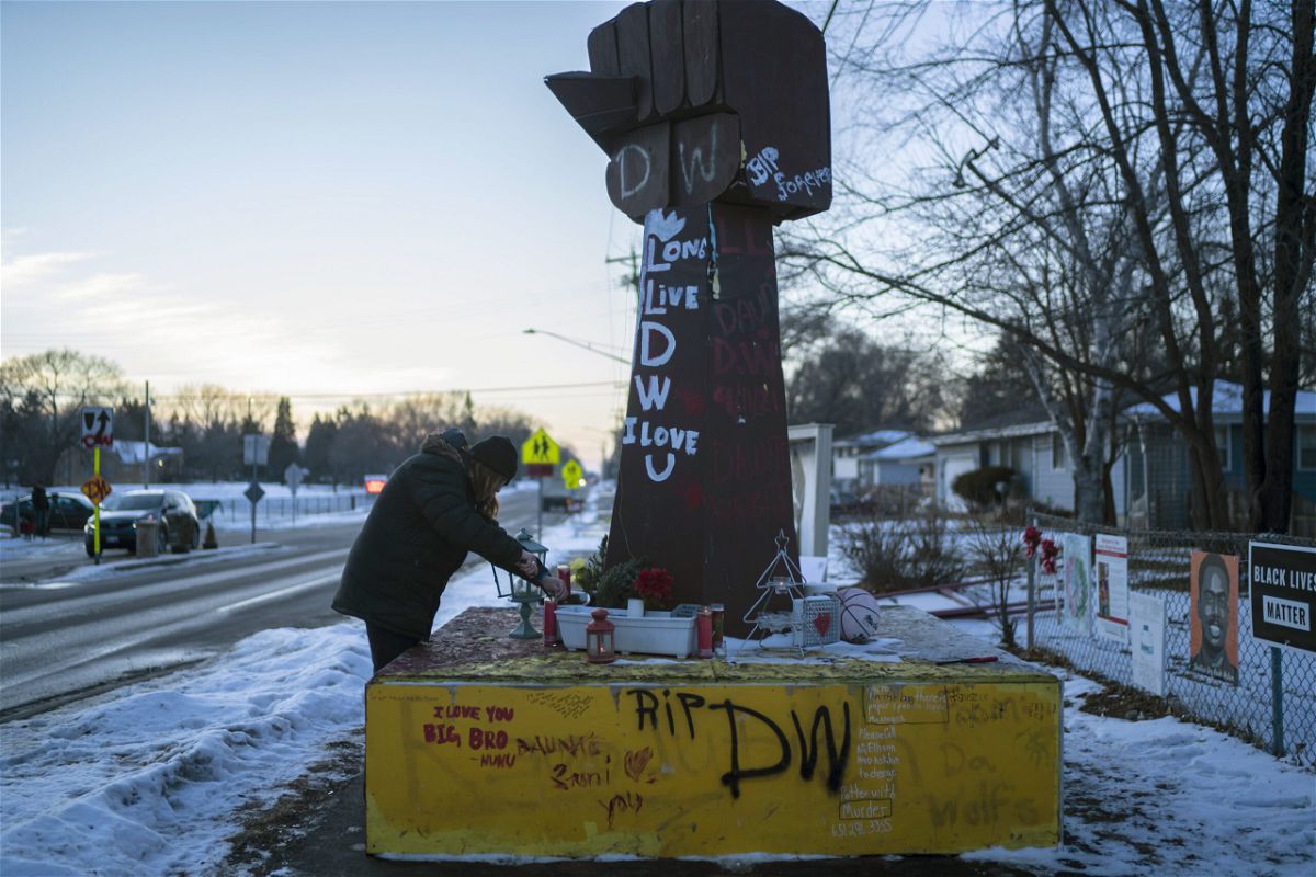 <i>Renée Jones Schneider/AP</i><br/>Michelle Filkins cleans up and lights candles at the Daunte Wright memorial after guilty verdicts were announced against former police officer Kimberly Potter on December 23