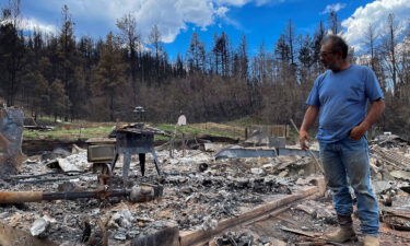 Daniel Encinias stands next to the ruins of his home