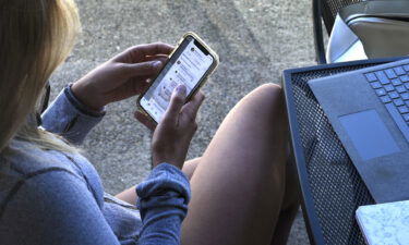 A young woman uses her smartphone outside a coffee shop in Jacksonville