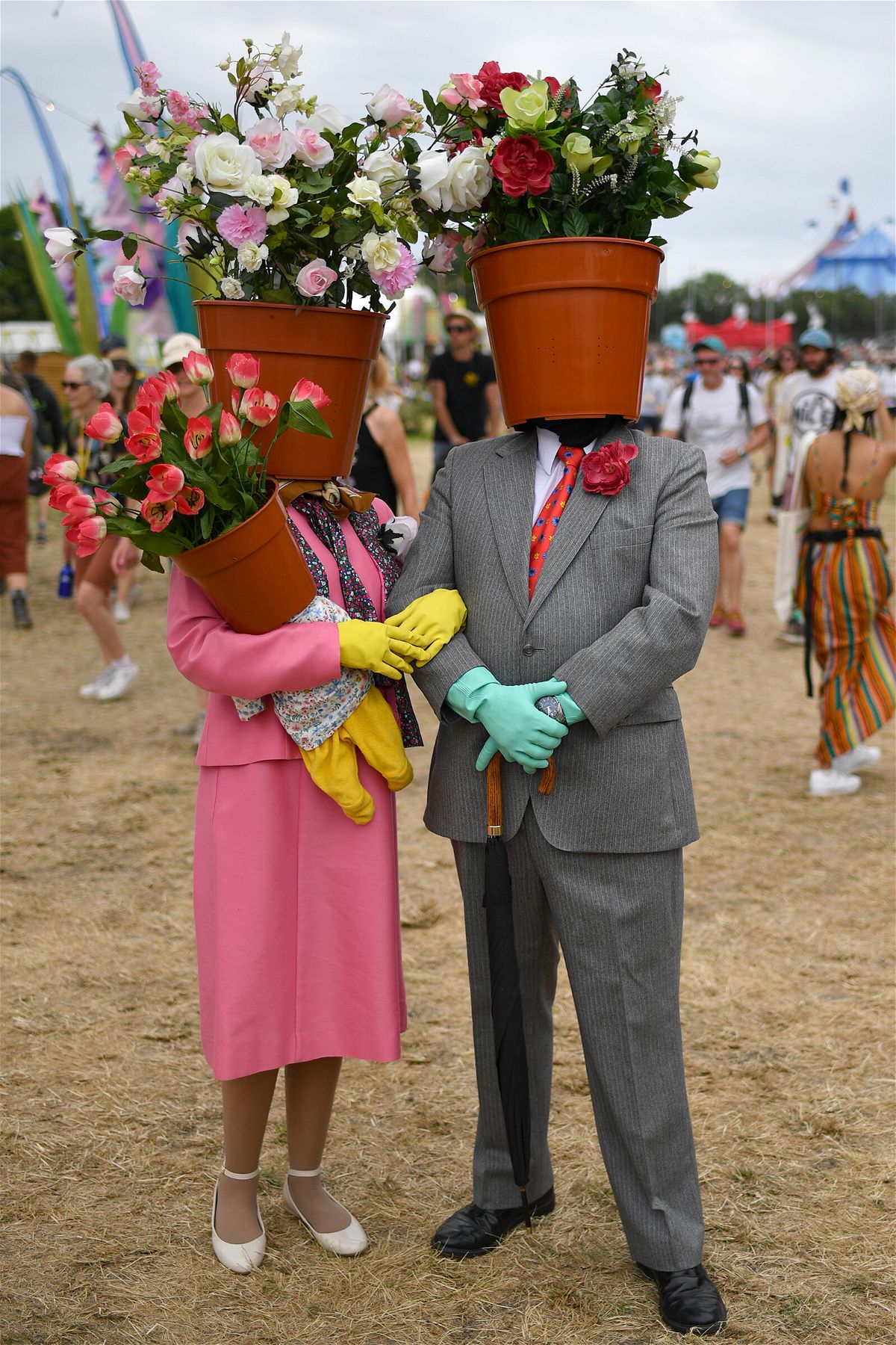 <i>Dave J Hogan/Getty Images</i><br/>A couple dressed as flower pots walk around the site during day two of Glastonbury.