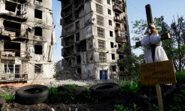 A grave is pictured in front of destroyed residential buildings in Mariupol on May 31