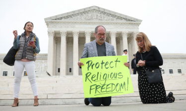 Demonstrators kneel in prayer outside the U.S. Supreme Court as the case of former Bremerton High School assistant football coach Joe Kennedy is argued before the court April 25 in Washington