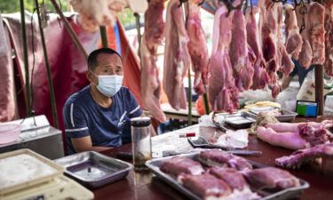 A vendor sells pork at an open market on May 31