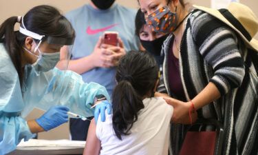 A girl receives the flu vaccination shot from a nurse at a free clinic held at a local library on October 14