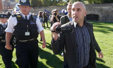 Blogger Graham Phillips is escorted away by police officers after he disrupted a press conference by Bellingcat founder Eliot Higgins