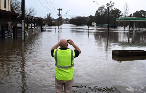 A local takes a photo of a road inundated by floodwaters in Camden in South Western Sydney