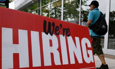 A man walks past a "now hiring" sign posted outside of a restaurant in Arlington