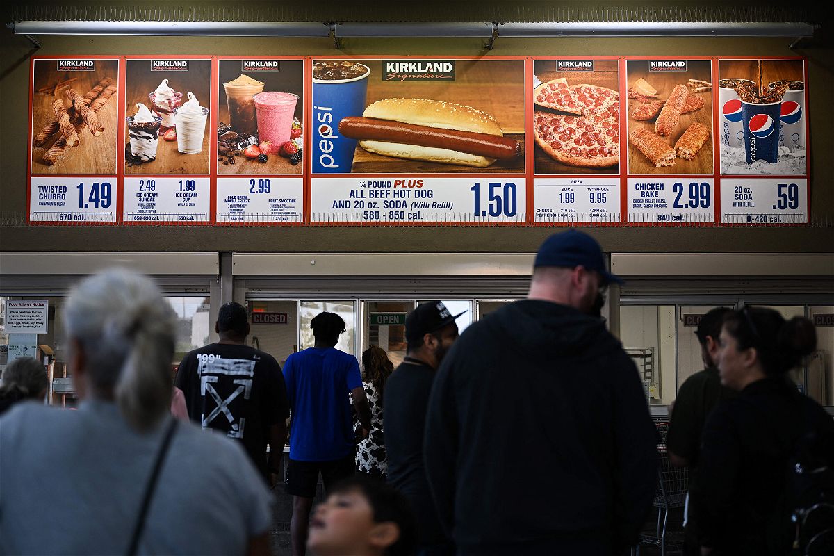 <i>Patrick T. Fallon/AFP/Getty Images</i><br/>Customers wait in line to order below signage for the Costco Kirkland Signature $1.50 hot dog and soda combo.