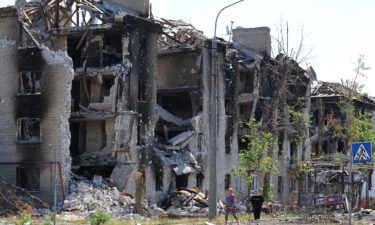 Local residents walk past apartment buildings destroyed during Ukraine-Russia conflict in the city of Sievierodonetsk in the Luhansk Region