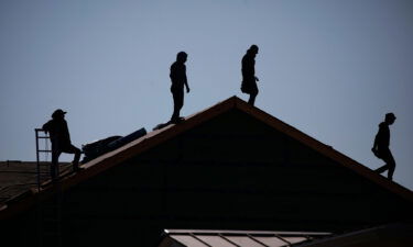 Contractors stand on the roof of a house under construction at the Norton Commons subdivision in Louisville