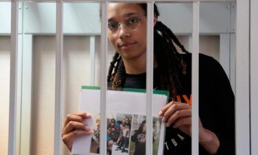 Brittney Griner holds photographs standing inside a defendant's cage before a hearing at a court outside Moscow on July 27.