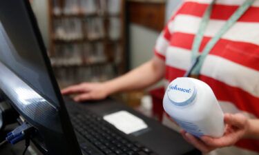Johnson & Johnson is abandoning talc-based baby powder in 2023 and instead will make it with cornstarch. A pharmacy cashier holds a bottle of Johnson & Johnson's baby powder in Salt Lake City in February 2021.