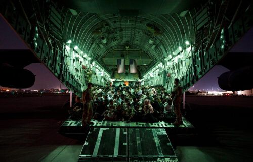 An air crew assigned to the 816th Expeditionary Airlift Squadron assists evacuees aboard an aircraft in support of the Afghanistan evacuation at Hamid Karzai International Airport on August 21