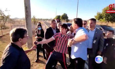 Brazil's president Jair Bolsonaro grabs YouTuber Wilker Leao's shirt as Leao demonstrates against Bolsonaro's government outside the Alvorada Palace in Brasilia