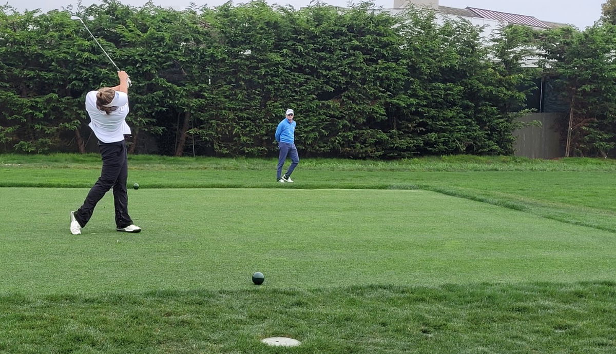 Kalea Hall teeing off on the 17th hole at Pebble Beach with her playing partner Steve Flesch looking on