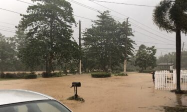 A man stands near a flooded road in Villa Blanca