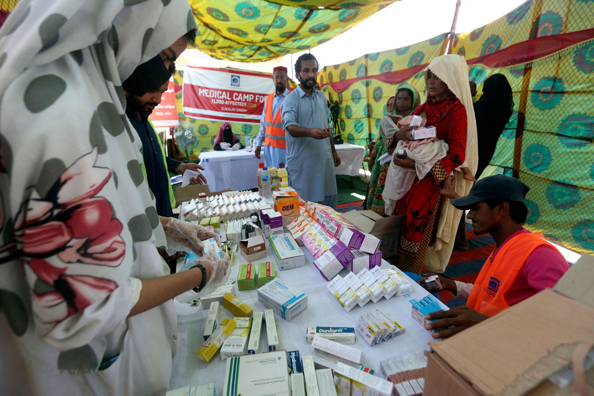 <i>Fareed Khan/AP</i><br/>Displaced families wait to receive medicine at a distribution point in Sukkur