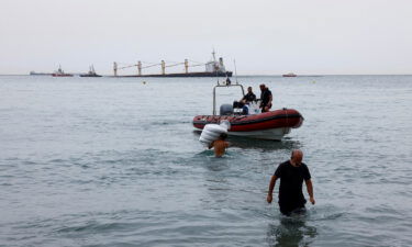 Workers carry floats to contain oil from the cargo ship OS 35