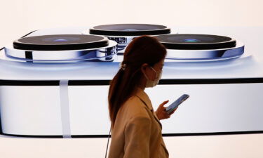 A woman walks past an image of an iPhone 13 Pro at an Apple Store on the day the new Apple iPhone 13 series went on sale