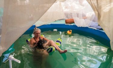 Dot of House of Dots art gallery relaxes in her pool with her dog as they cool off amid a heatwave on August 31 in Slab City