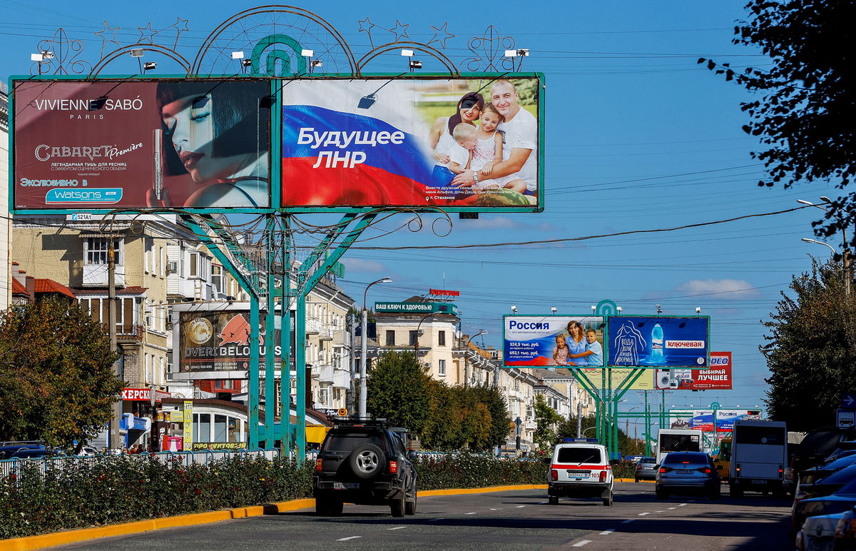 <i>Alexander Ermochenko/Reuters</i><br/>Vehicles drive past advertising boards displaying pro-Russian slogans in a street in Luhansk