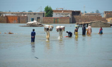 Flood victims wade through flood waters