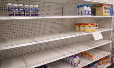 Similac and Enfamil products are seen on largely empty shelves in the baby formula section of a Target store