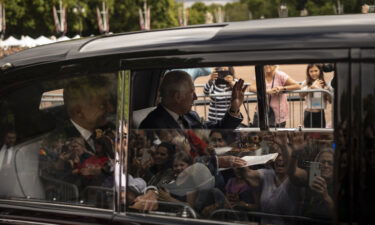 King Charles III greets supporters as he arrives at Buckingham Palace.