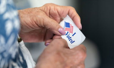 Election deniers are running for important offices around the country in the November 8 midterms and pictured a poll worker holds a sticker that reads