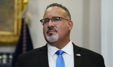 Education Secretary Miguel Cardona listens as President Joe Biden speaks about student loan debt forgiveness at the White House on August 24.