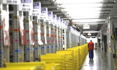 A worker transports plastic crates filled with orders to be shipped to customers at the Amazon Fulfillment Center in Moreno Valley