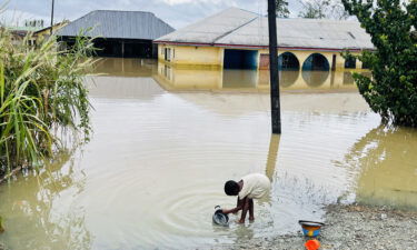 A child is pictured doing her dishes in floodwater in Odi