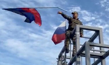 A member of the Ukrainian troop brings down a Donetsk Republic flag hoisted on a monument in Lyman