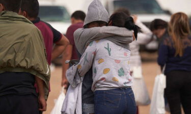 Migrants hug as they wait to be processed by US Border Patrol after they illegally crossed the US southern border with Mexico on October 9 in Eagle Pass