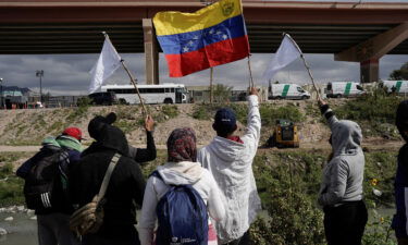 Migrants wave flags on the banks of the Rio Grande Tuesday while peacefully protesting the new US migration enforcement rules.