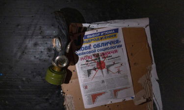 A view of a newspaper and a gas mask hung on a wall at a room in a police station which an Ukrainian serviceman says was used as a torture chamber by Russian soldiers in the town of Izium in Kharkiv region