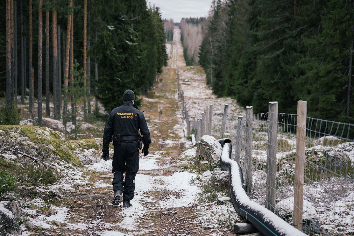 <i>Alessandro Rampazzo/AFP/Getty Images</i><br/>Senior border guard officer Juho Pellinen walks along a fence marking the boundary area between Finland and Russia on November 18. Finland has proposed to spend 139 million euros ($143 million) on building barrier fences on its eastern border with Russia in 2023.