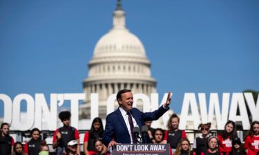 Connecticut Democratic Sen. Chris Murphy speaks with students wearing body armor stand behind him on a stage during a gun safety reform rally near the Capitol Reflecting Pool in Washington