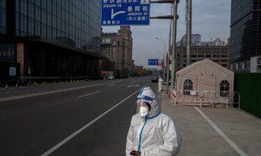 An epidemic control worker wears protective clothing to protect against the spread of COVID-19 as she stands in a nearly empty street in the Central Business District on November 23