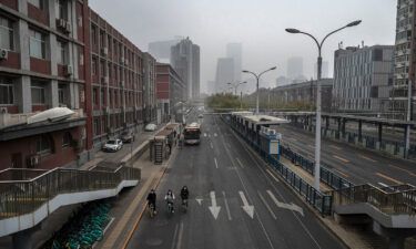 People ride bikes on an empty street near Beijing's central business district on November 24.