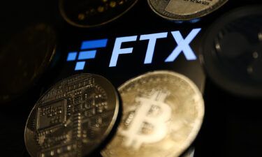 An FTX logo is displayed on a phone screen and representation of cryptocurrencies are seen in this illustration photo taken on November 14.