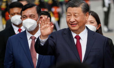 Chinese President Xi Jinping (R) waves as he arrives in Bali