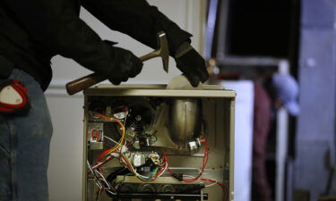 A worker prepares to install a new Carrier natural gas furnace at a residential home in Spanish Fork