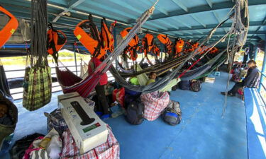 Foreign and Peruvian tourists wait in the boat where they have been detained at the Cuninico community in Loreto in the north of Peru